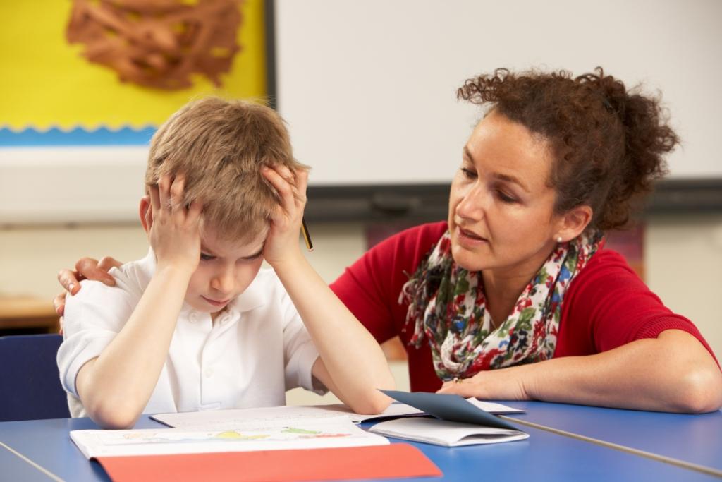 frustrated_school_boy_working_with_teacher_in_the_classroom.jpg